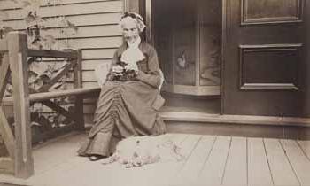 贝琪·怀尔德坐在广场上，狗在她的脚边